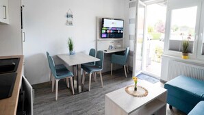 A modern room with a dining table, chairs, a TV mounted on the wall, and a sofa.