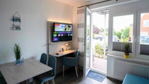 A modern room with a desk, two chairs, a TV, and a window with a view of the outside.