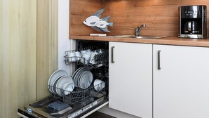 Uma cozinha com lava-louças, cafeteira e painel de madeira.