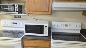Une cuisine avec des meubles de rangement en bois, un four à micro-ondes, une cuisinière et un four traditionnel.