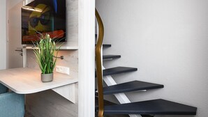 En modern trappa med en minimalistisk design, en platt-TV som är monterad på väggen och en liten krukväxt på en bänk.