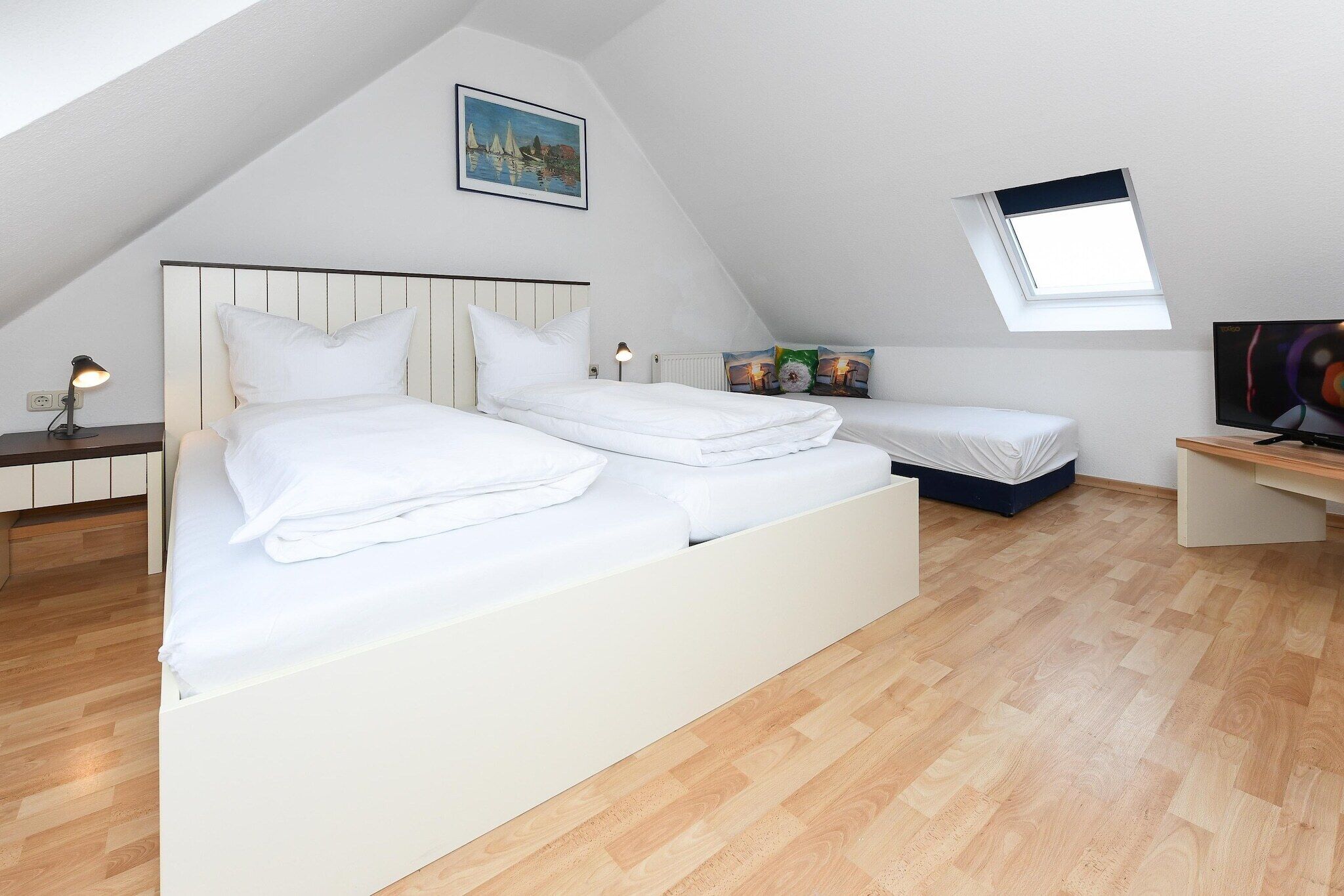 A bedroom with two beds, a skylight, a painting, and a TV.