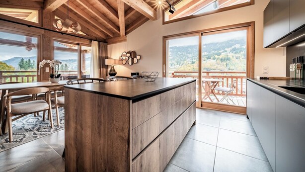 A modern kitchen with a large island, wooden ceiling beams, and large windows offering a view of the mountains. - Ardelle - alpine duplex with hot tub, Les Gets (Les Gets)
