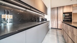 A modern kitchen with a black countertop, stainless steel appliances, and wooden cabinets. - Ardelle - alpine duplex with hot tub, Les Gets (Les Gets)