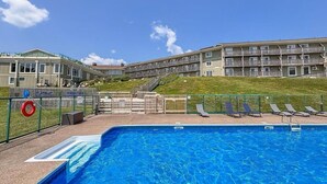 Ein Swimmingpool mit Liegestühlen und ein Gebäude mit mehreren Balkonen im Hintergrund.