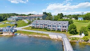 A hotel with a large building and a smaller structure with a row of windows. There is a dock with boats and a body of water in front.