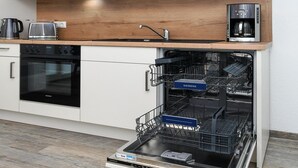 A modern kitchen with a built-in dishwasher, a coffee maker, and a Siemens oven. - Moderne Ferienwohnung mit Terrasse in ruhiger Lage (Bensersiel)