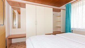 A bedroom with a bed, wooden wardrobe, and a bench. - Geräumige Ferienwohnung mit Terrasse in Bensersiel (Bensersiel)