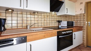 A kitchen with white cabinets, a wooden countertop, a built-in microwave, and an oven. - Geräumige Ferienwohnung mit Terrasse in Bensersiel (Bensersiel)