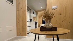 A modern kitchen with wooden cabinetry, a round wooden table with a vase, and a tiled floor. - Cabañas Camiño do Mar  (Foz)
