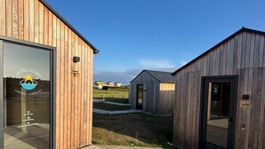 A wooden building with a glass entrance and a wooden deck. - Cabañas Camiño do Mar  (Foz)