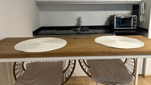 Una cocina con dos individuales redondos blancos sobre una mesa de madera, un microondas y un lavamanos.