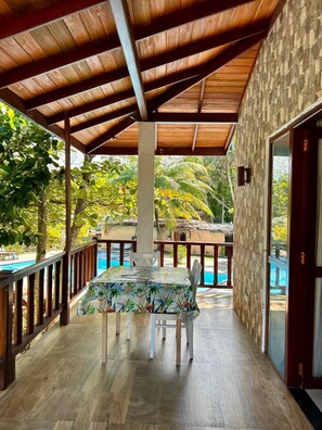 Ein überdachter Außenbereich mit Pool, Holzdeck und einem Tisch mit Blumenmuster-Tischdecke.