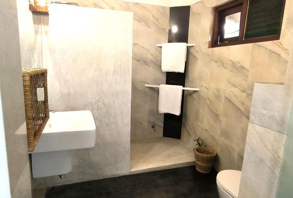 A bathroom with a white sink, a shower, and a toilet. There are towels hanging on a rack.