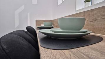 Un comedor moderno con una mesa de madera y un cojín negro. Hay dos cuencos verdes y un plato a juego sobre la mesa.