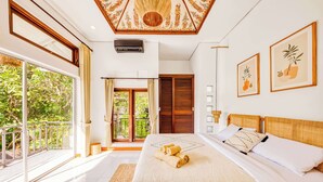 Un dormitorio con una cama grande, vistas a la vegetación por la ventana y un ventilador de techo.