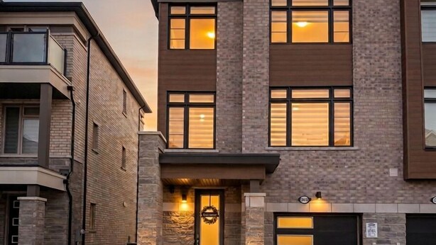 Un immeuble résidentiel de deux étages, doté d’un garage, d’une entrée principale avec une porte et d’un petit jardin.