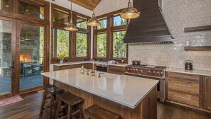 Una cocina amplia con una isla grande, armarios de madera y una chimenea de piedra.
