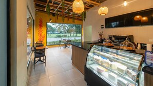 Interior de una cafetería con mostrador, vitrina y lámparas colgantes.