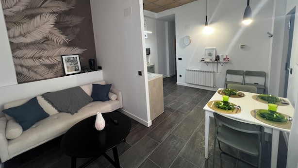 Ein modernes Wohnzimmer mit einer Couch, einem Couchtisch und einem Essbereich mit Tisch für zwei Personen.