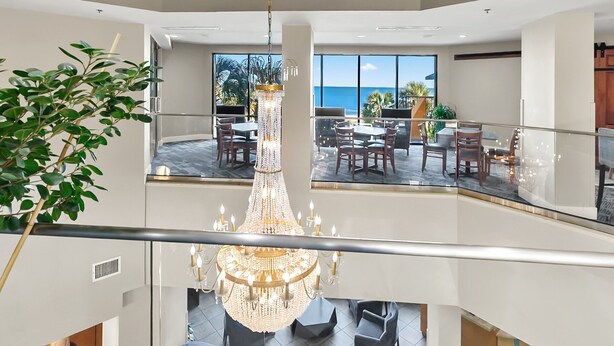 Un intérieur moderne agrémenté d’un grand lustre, d’un balcon offrant une vue sur l’océan et d’un coin repas.