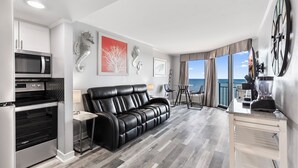 Une chambre d’hôtel moderne dotée d’une cuisine, d’un canapé en cuir et d’un balcon offrant une vue sur la mer.