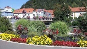 A building with a red roof, surrounded by a variety of colorful flowers and plants. - Becci`s Apartment- Free Parking (Kapfenberg)