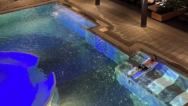 A multi-level indoor swimming pool with lounge areas and a clock on the wall. - Becci`s Apartment- Free Parking (Kapfenberg)