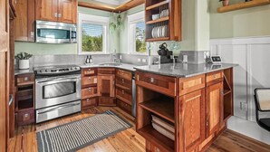 A compact kitchen with wooden cabinets, stainless steel appliances, and a small island. - Affordable Waterfront Luxury!  "Jewel of Carrabelle" Perfect Condo on the Cove! (Carrabelle)