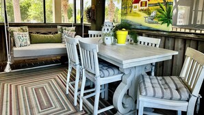 A cozy seating area with a wooden bench, white chairs, and a table with potted plants. - Affordable Waterfront Luxury!  "Jewel of Carrabelle" Perfect Condo on the Cove! (Carrabelle)