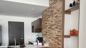 A modern kitchen with a wooden island, built-in cabinets, and a brick accent wall.