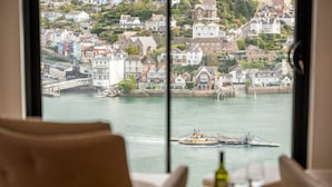 A view from a window overlooking a harbor with boats, a bridge, and a town with colorful houses. - Luxury Riverside Retreat in Dartmouth with views (Dartmouth)