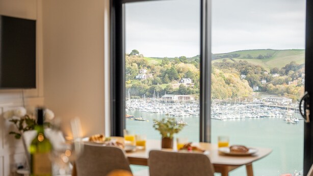 A dining area with a view of a marina and hills. - Luxury Riverside Retreat in Dartmouth with views (Dartmouth)