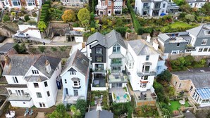 A residential area with modern houses featuring large windows, balconies, and well-maintained gardens. - Luxury Riverside Retreat in Dartmouth with views (Dartmouth)