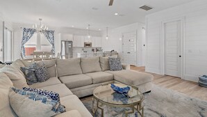 A modern living room with a sectional sofa, a glass coffee table, and a ceiling fan. - 🏖️Luxury 6BR-Private Pool-Scattered, Smothered, & Covered🏖️ (Miramar Beach)