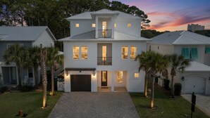 A two-story house with a front garage, a balcony on the second floor, and a driveway leading to the entrance. - 🏖️Luxury 6BR-Private Pool-Scattered, Smothered, & Covered🏖️ (Miramar Beach)