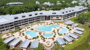 Un complexe hôtelier doté de plusieurs piscines, d’espaces extérieurs aménagés et d’un grand bâtiment avec des balcons.