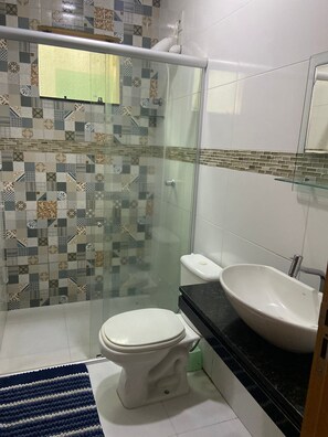 Chuveiro, toalhas de banho, sabonete, papel higiênico