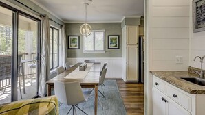 A modern kitchen with a granite countertop, a built-in sink, and a dining area with a wooden table and chairs. - Coastal Escape w/ Pool & Ocean Peek! (Hilton Head Island)