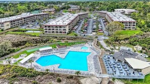 A resort with multiple buildings, a large swimming pool, and outdoor seating areas. - Coastal Escape w/ Pool & Ocean Peek! (Hilton Head Island)