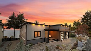 Ein modernes Haus mit Terrasse, kleiner Veranda und Blick auf das Meer bei Sonnenuntergang.