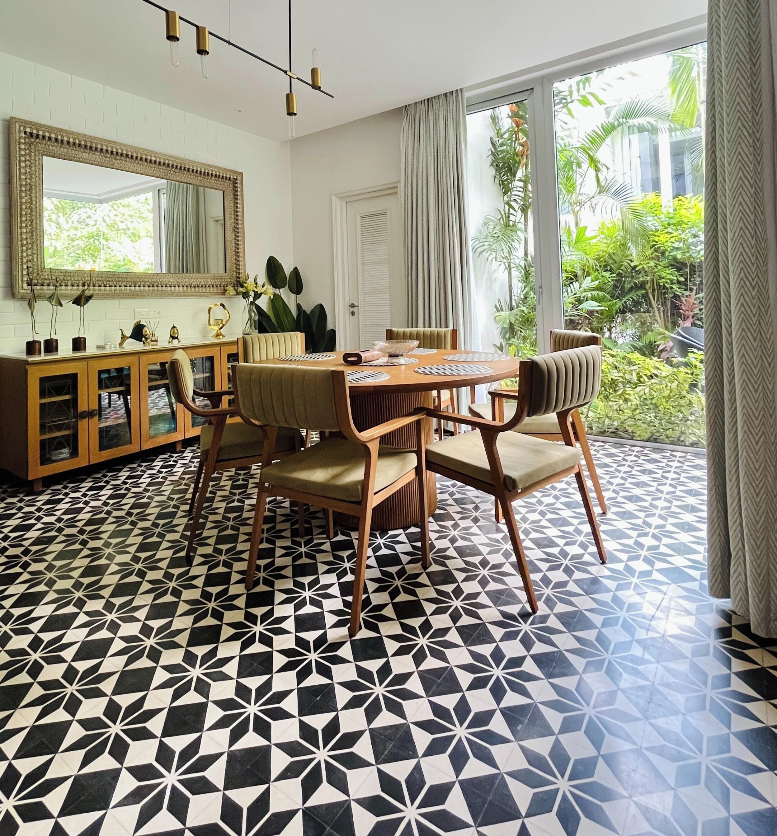 Un coin repas avec un sol à motifs géométriques, une table à manger en bois avec des chaises, un buffet avec des portes en verre et un grand miroir au-dessus de la table.