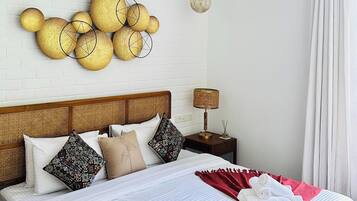 A hotel room with a bed, a wall-mounted decorative item, a hanging light fixture, and a nightstand with a lamp.