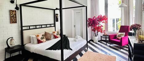 A four-poster bed with a black frame, a white headboard, and multiple pillows.