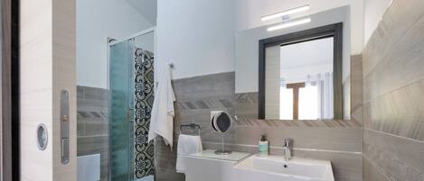 Un baño moderno con cabina de ducha de vidrio, un lavabo blanco y un espejo.