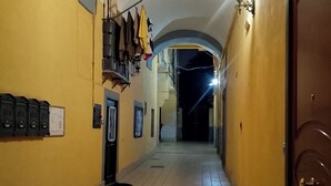 A corridor with tiled flooring, a yellow wall, and a wooden door on the right.