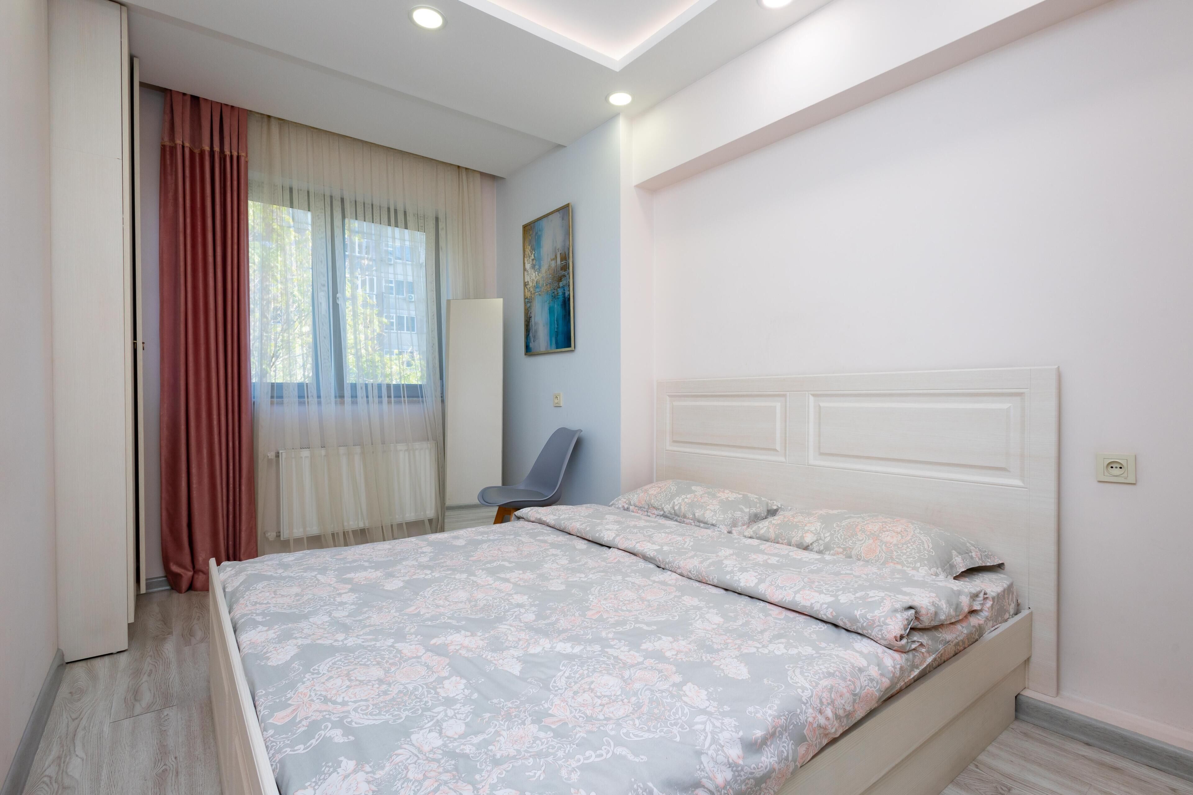 Un dormitorio con cama, una silla y un cuadro en la pared.
