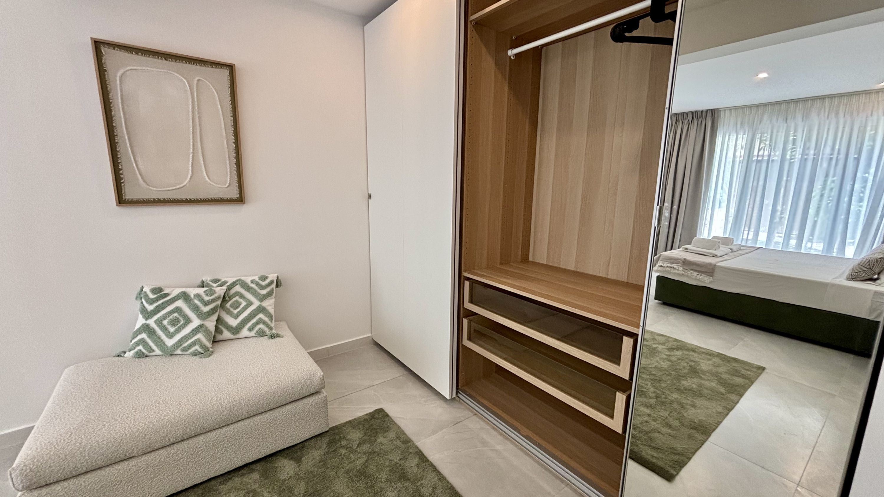 A modern bedroom with a built-in closet, a bedside table, and a view of the bathroom.