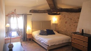 A bedroom with a wooden bed, a nightstand with a lamp, a dresser, and a hanging clothes rack. - Large Art Nouveau house between sea and garrigue, charm and leisure in the heart of the South of France (Gabian)
