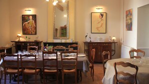 A dining area with wooden tables and chairs, a chandelier, and artwork on the walls. - Large Art Nouveau house between sea and garrigue, charm and leisure in the heart of the South of France (Gabian)
